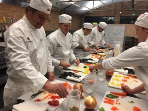 5 chefs in the kitchen preparing a meal