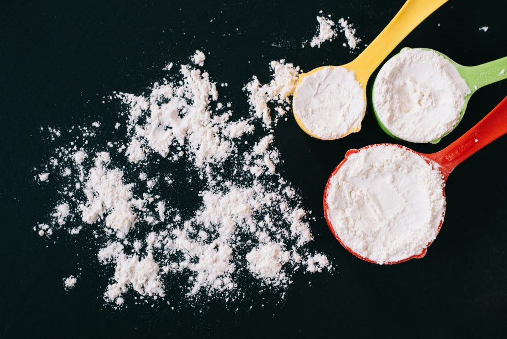 top view of a flour in a colorful measuring cup on black background. concept of cooking,bakery and food ingredient