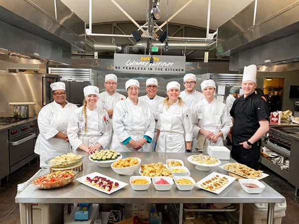 A Park City Culinary Institute class in the kitchen showing off the dishes they've prepared.