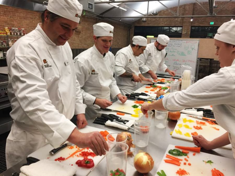 Park City Culinary Institute students working in the teaching kitchen, practicing chopping vegetables.