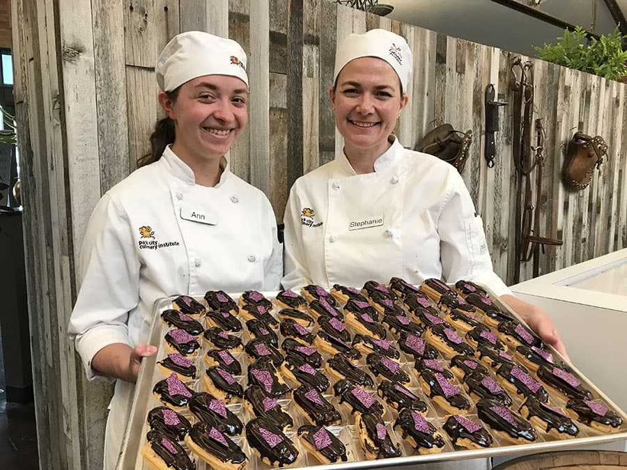 Two Park City Culinary Institute students proudly showing off their chocolate eclairs.